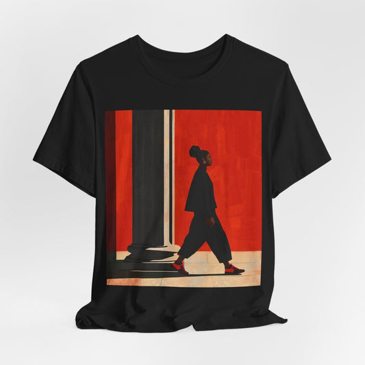 Unisex shirt featuring a Black woman with an afro puff walking past a red wall, dressed in all black with red sneakers.