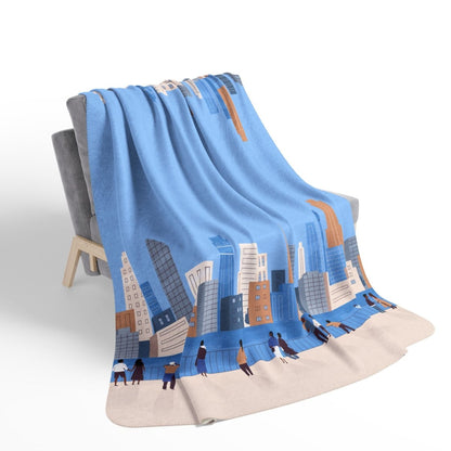 Folded blanket with cityscape design on a chair against a white background