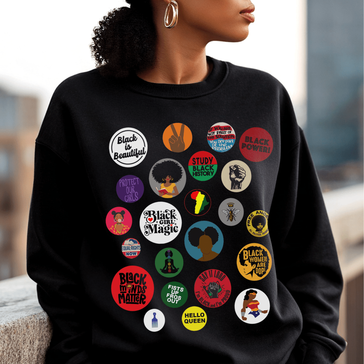 Sweatshirt with button-style designs celebrating Black culture, featuring phrases, symbols, and illustrations in a grid.