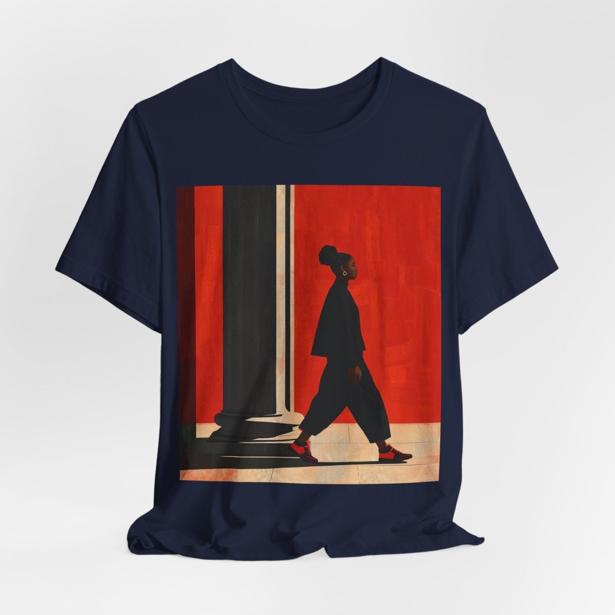 Unisex shirt featuring a Black woman with an afro puff walking past a red wall, dressed in all black with red sneakers.