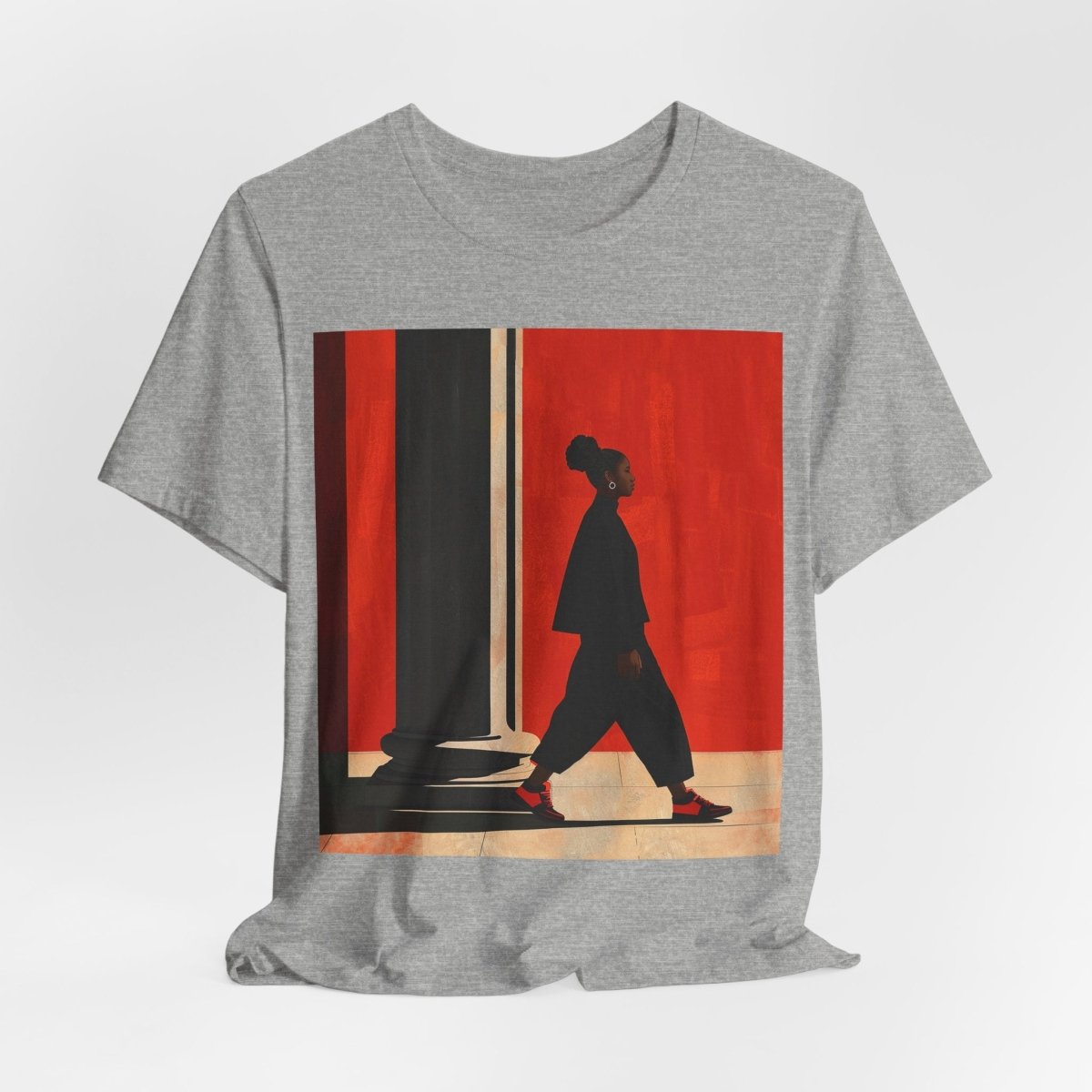 Unisex shirt featuring a Black woman with an afro puff walking past a red wall, dressed in all black with red sneakers.